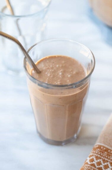 chocolate peanut butter banana smoothie in glass with a straw