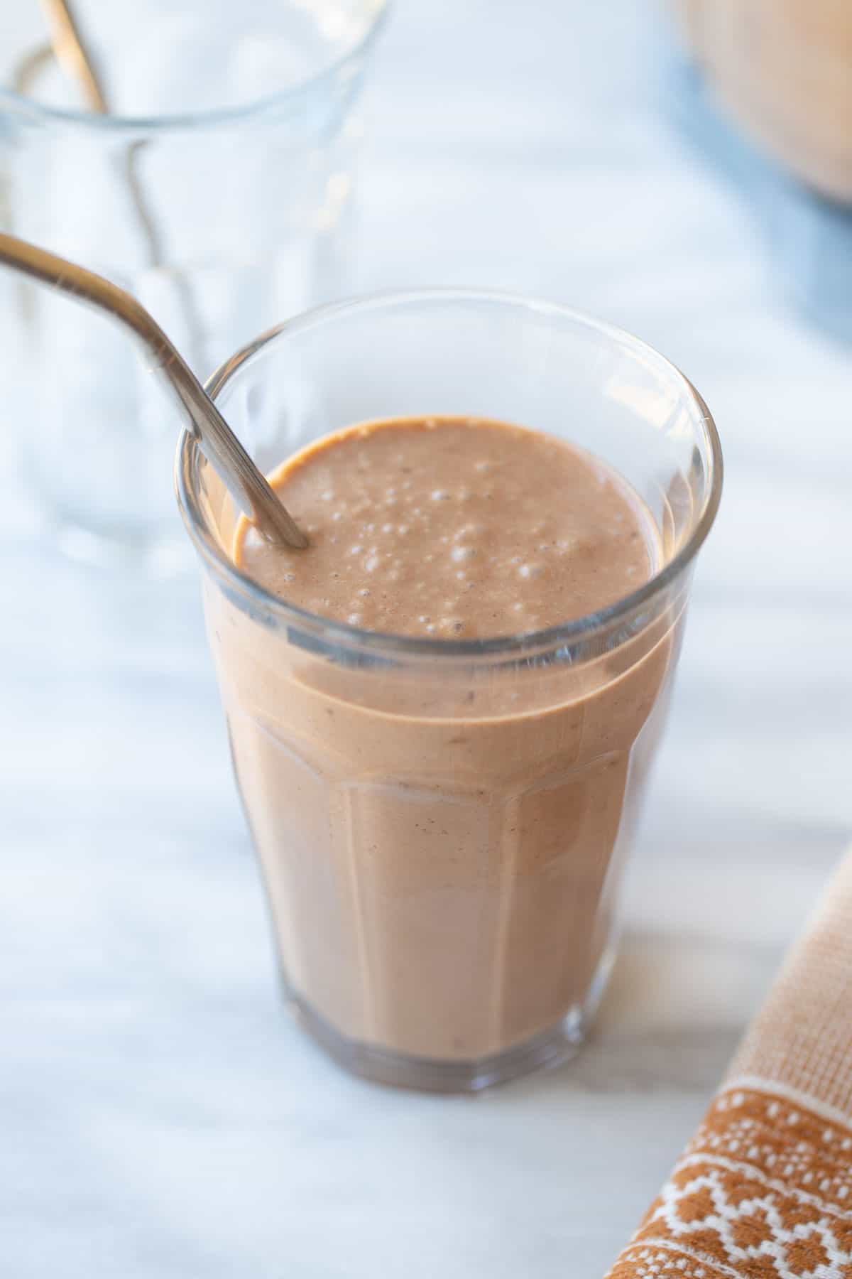 chocolate peanut butter banana smoothie in a glass with a straw