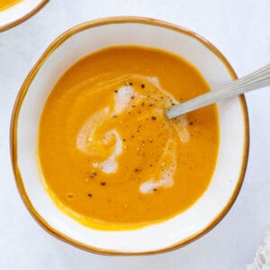 roasted sweet potato soup in a white bowl with a spoon