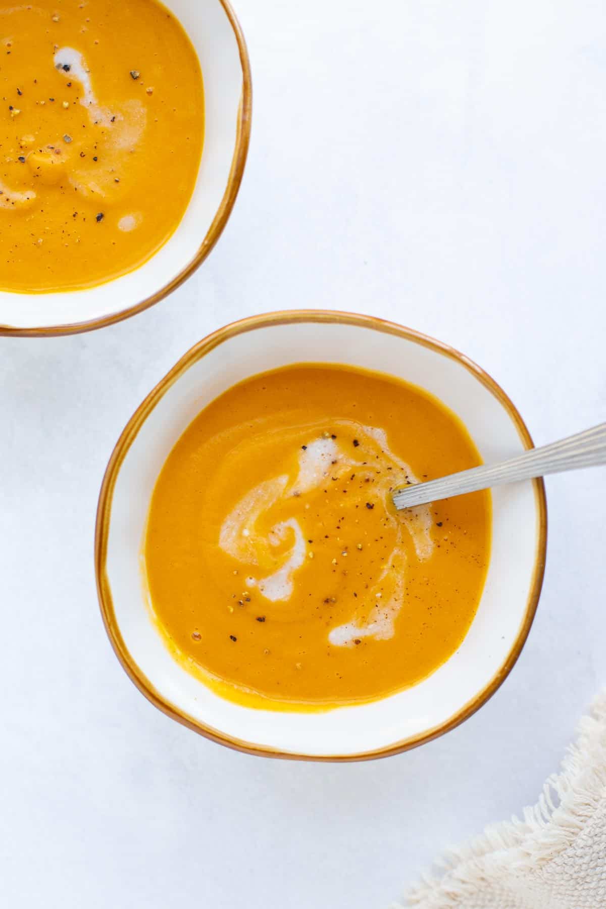 Bowls of creamy soup swirled with coconut milk and pepper