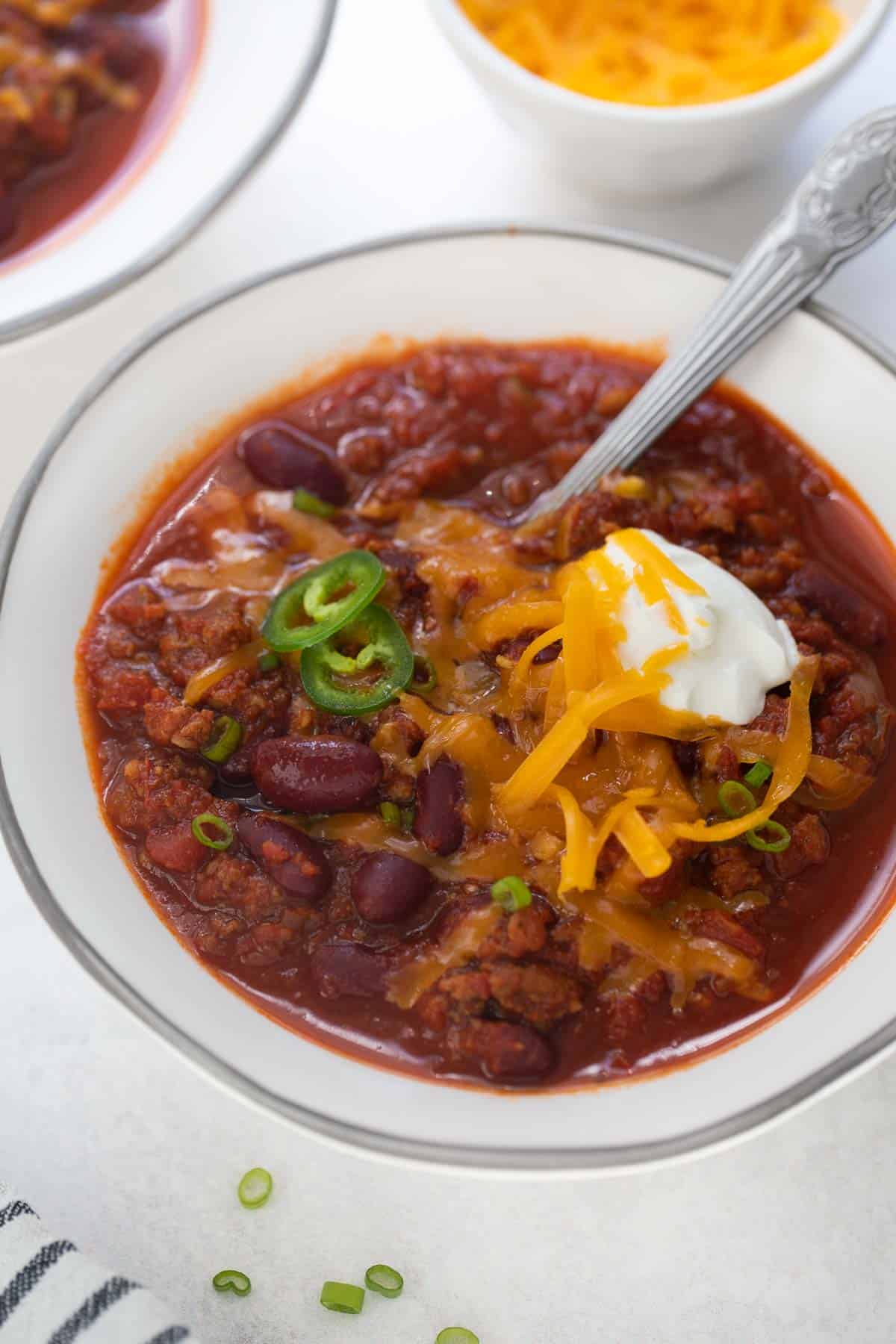 gluten-free chili in white bowl topped with sour cream and cheese