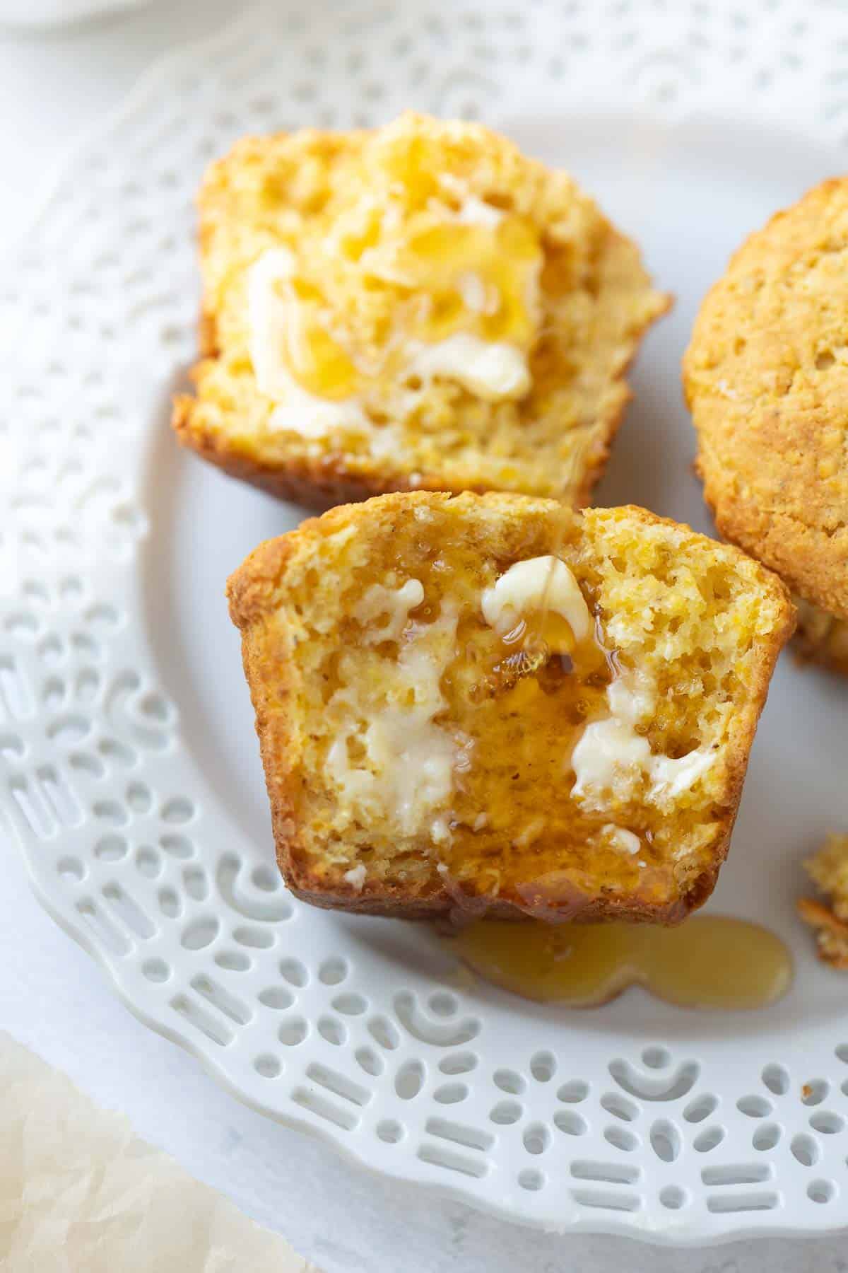 corn muffin on white plate with drizzle of honey
