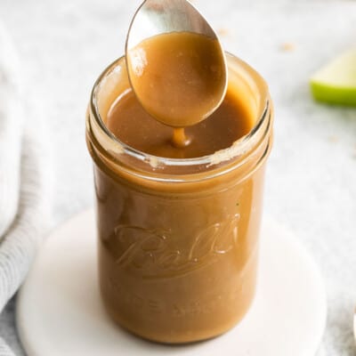 A spoonful of caramel touching a jar