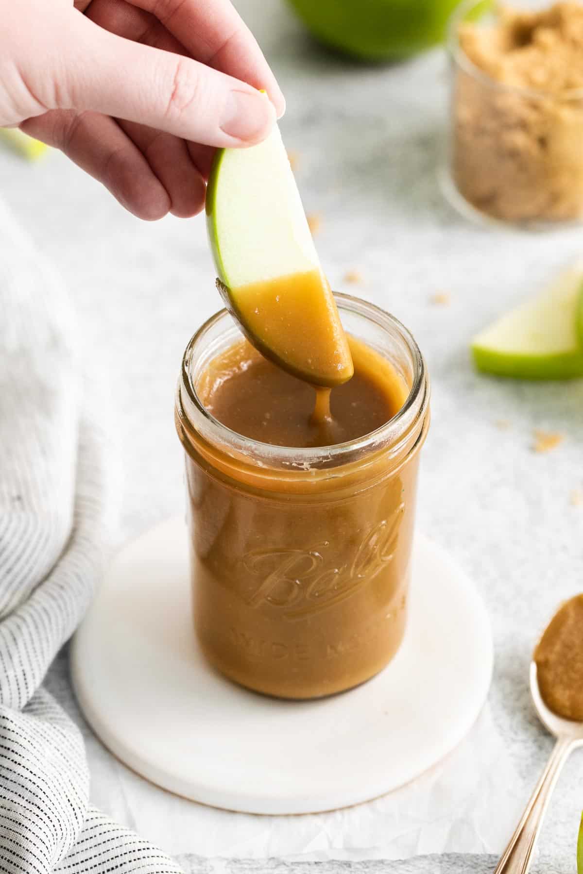 Dairy-free caramel in a jar with a spoon in it
