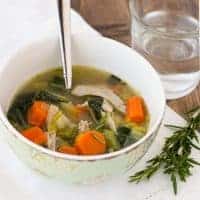 chicken soup in bowl with spoon and glass of water