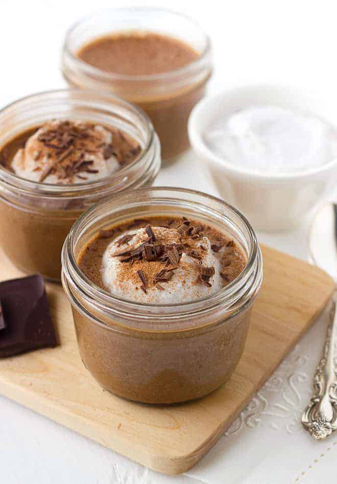 2 servings of chocolate chia pudding garnished with whipped cream and chocolate shavings in ½ pint glass jars