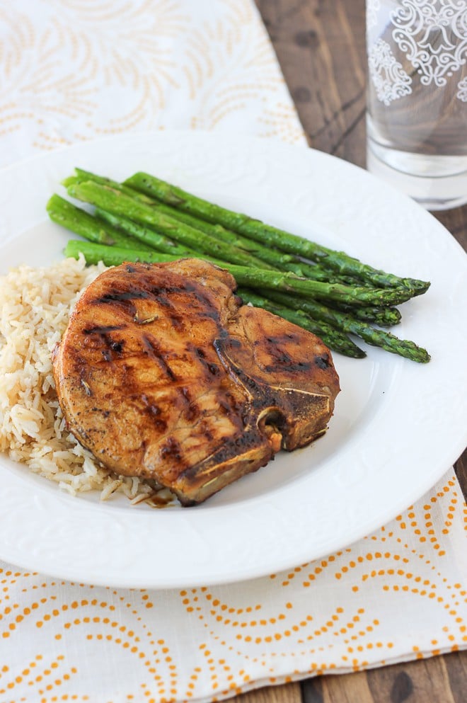 Honey-glazed pork chops with rice and asparagus on a white plate