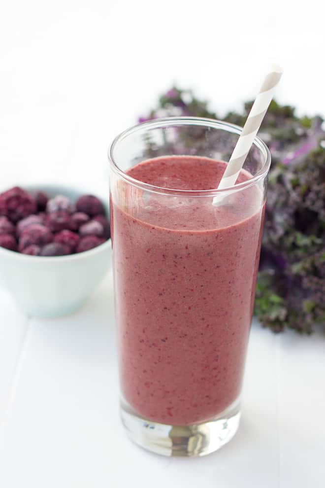 Sideview of a smoothie with berries in the background