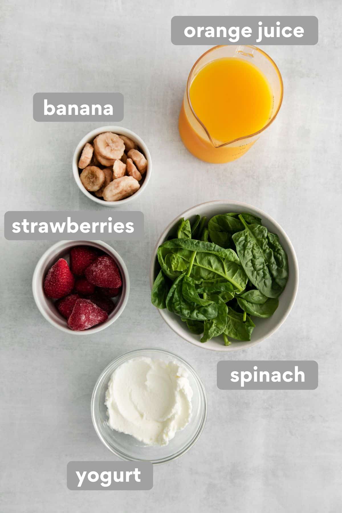 An overhead view of strawberry spinach smoothie ingredients on a counter top