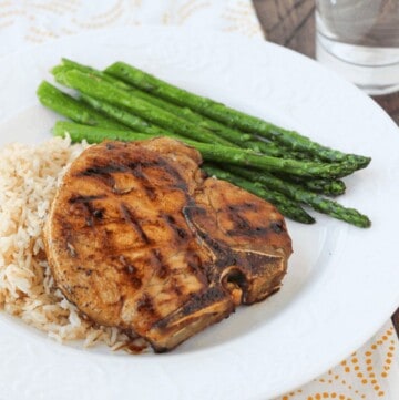 Honey-glazed pork chops with rice and asparagus on a white plate