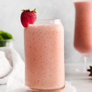 Strawberry spinach smoothie in a glass with a fresh strawberry on top