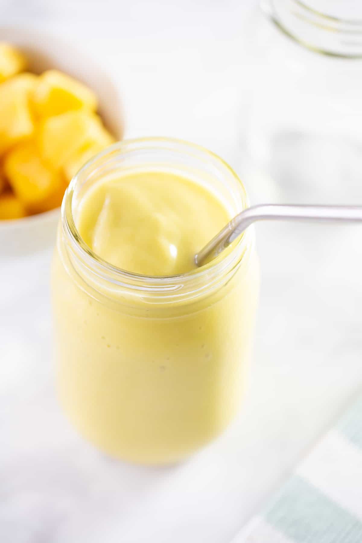 mango smoothie in glass jar with straw