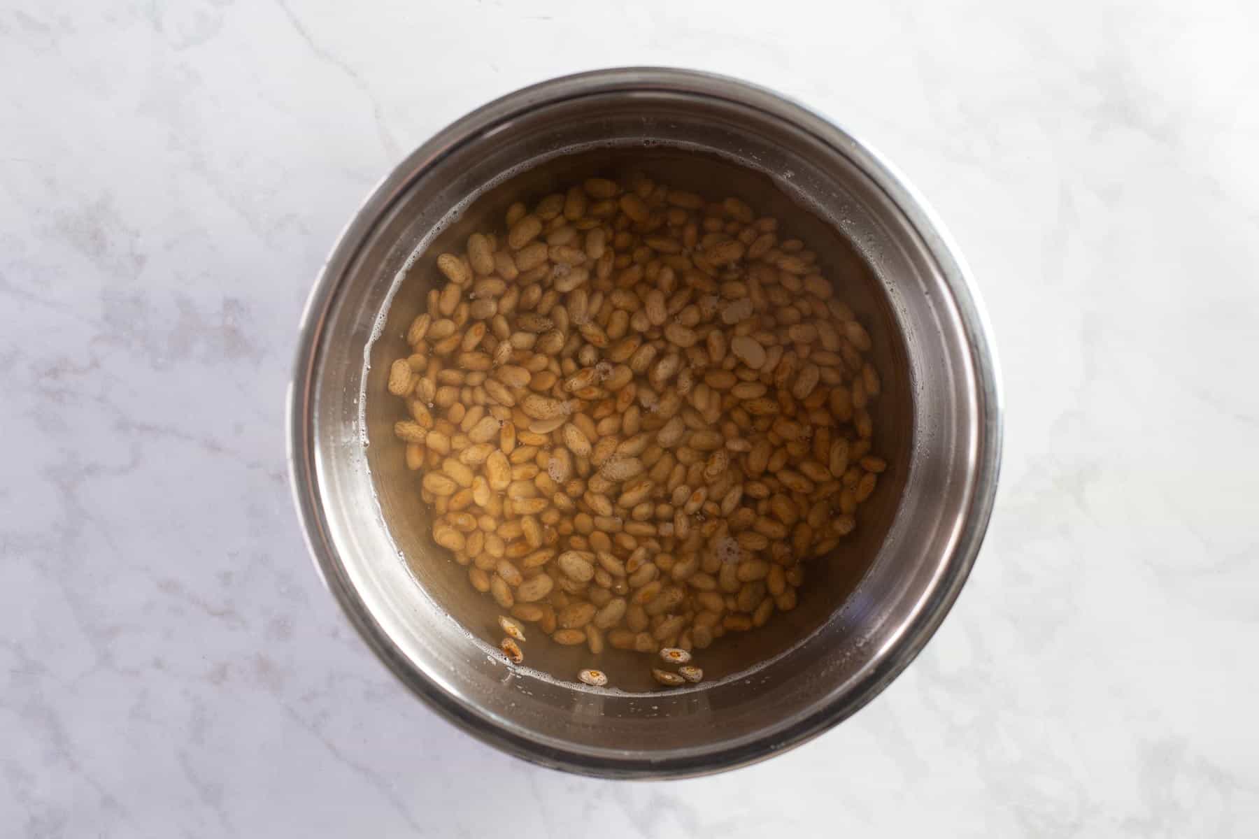 soaking dry pinto beans in a large steel pot