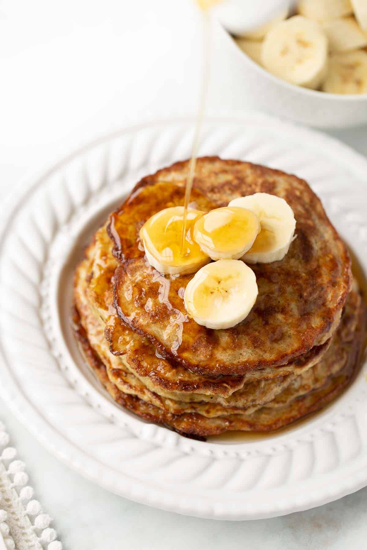 syrup being poured on banana pancakes