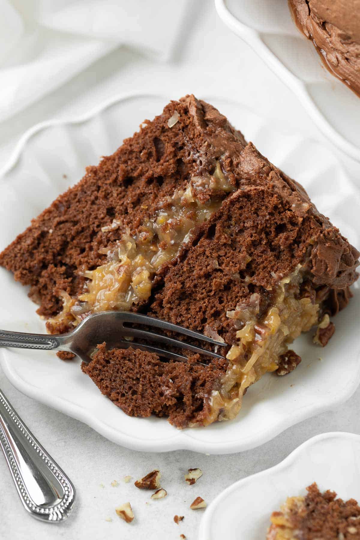 A slice of German chocolate cake on a plate, with a fork taking a bite