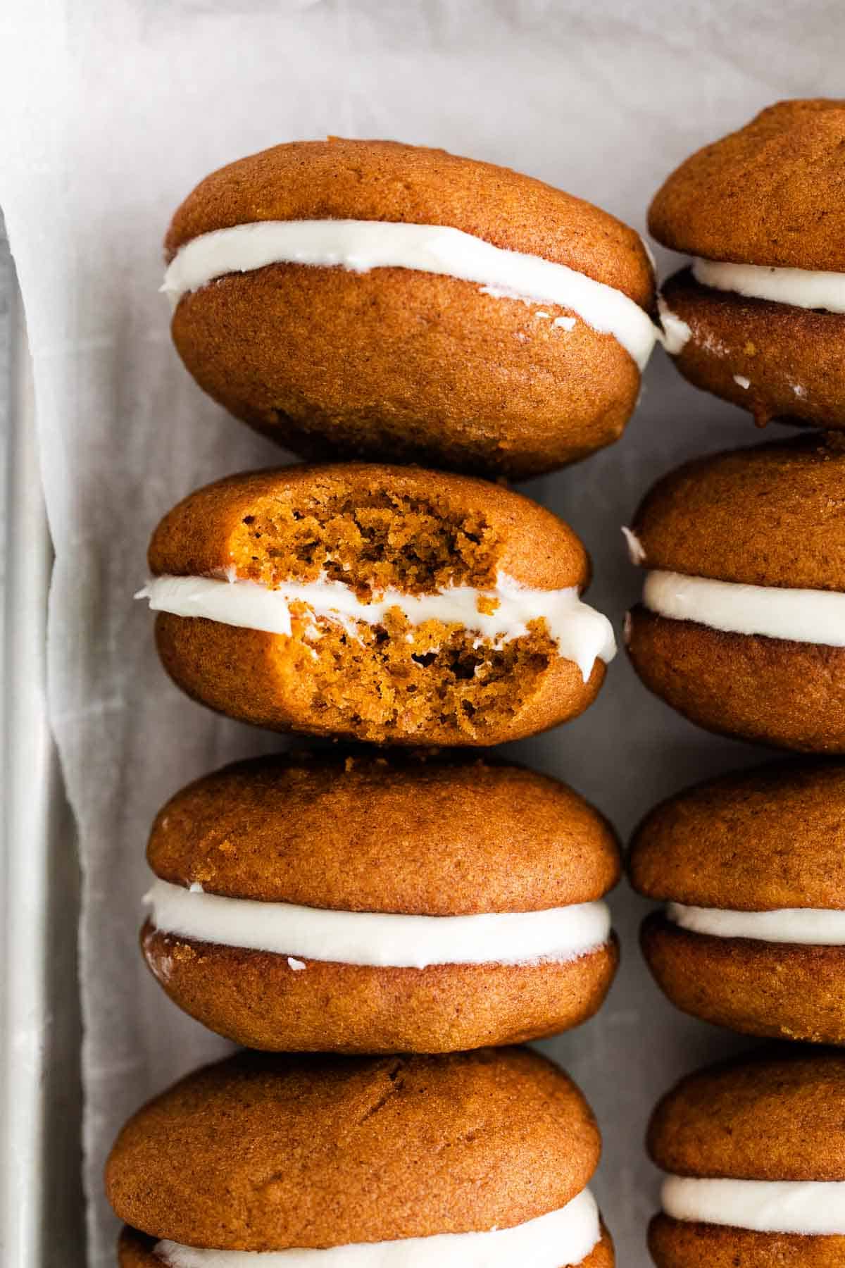 A closeup shot of pumpkin whoopie pies with a bite taken out of one