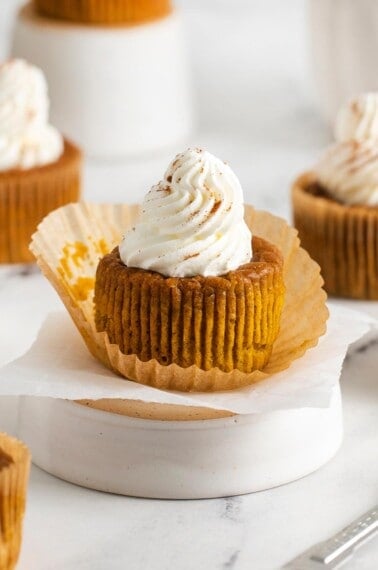 close up of crustless pumpkin pie topped with whipped cream on white surface