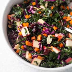 close up shot of kale salad in white bowl with serving spoon