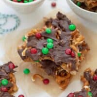 gluten free christmas pretzel treats on parchment paper topped with M&Ms
