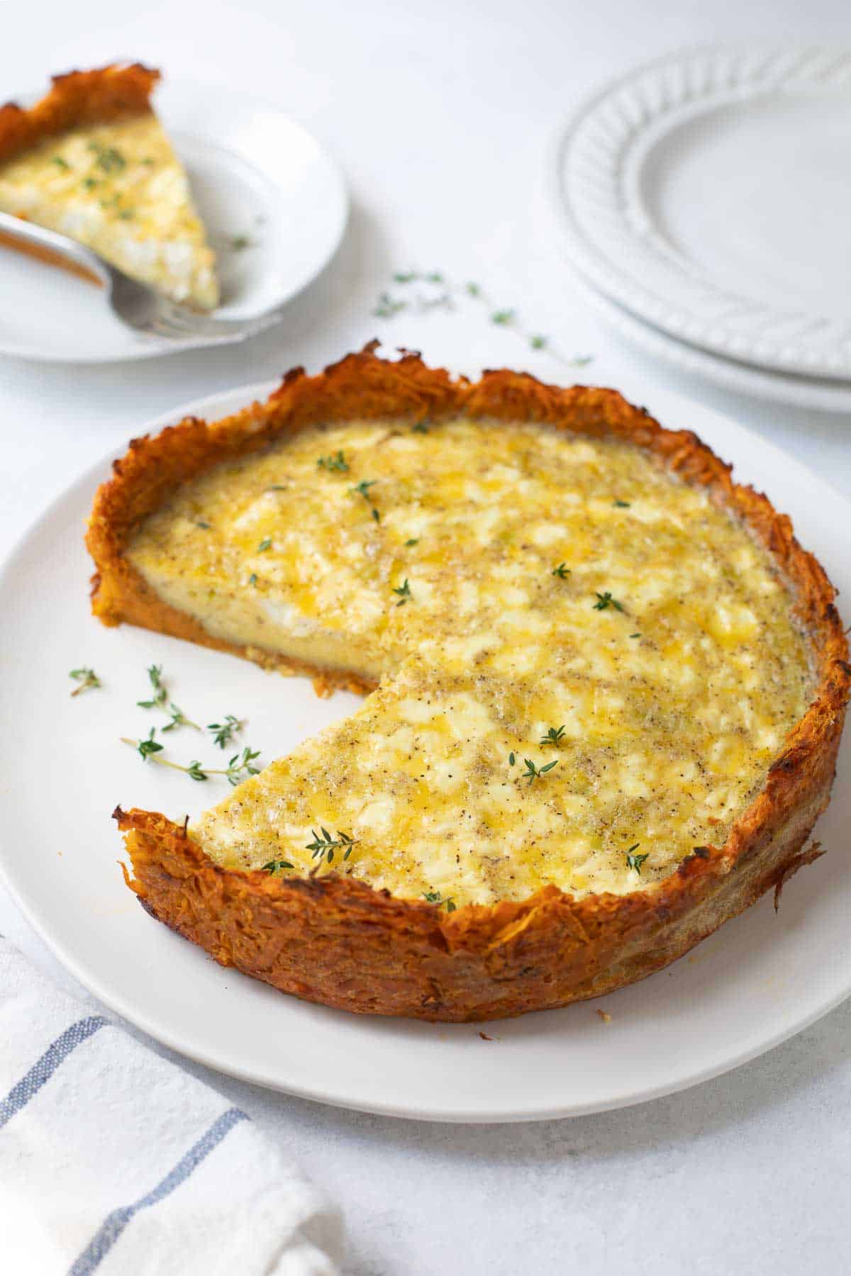 sweet potato crust quiche on white plate topped with thyme