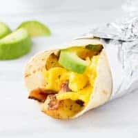 gluten-free breakfast burrito wrapped in foil on marble background