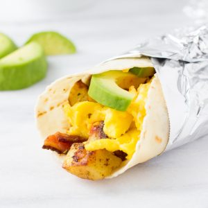gluten-free breakfast burrito wrapped in foil on marble background