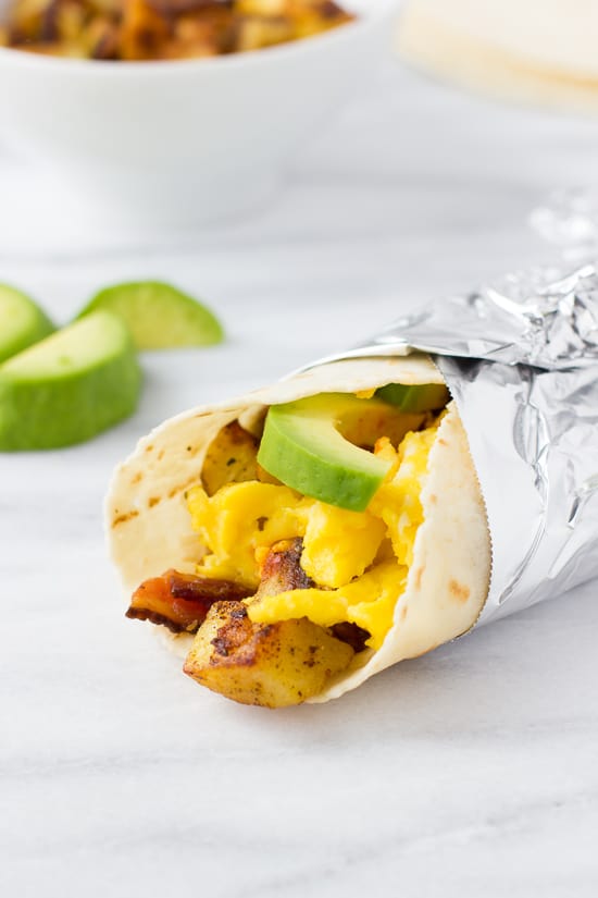 close up shot of gluten-free breakfast burrito wrapped in foil with avocado