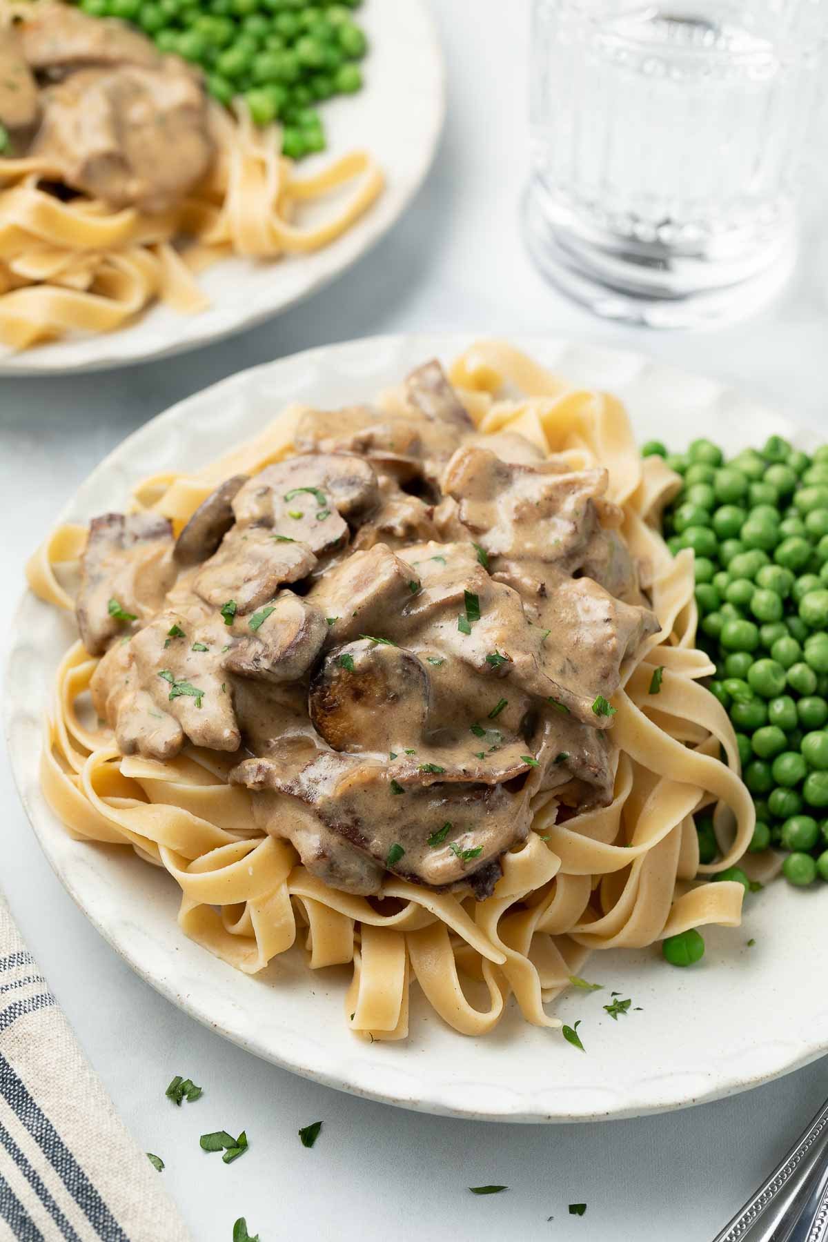 Gluten-free beef stroganoff plated with steamed peas.