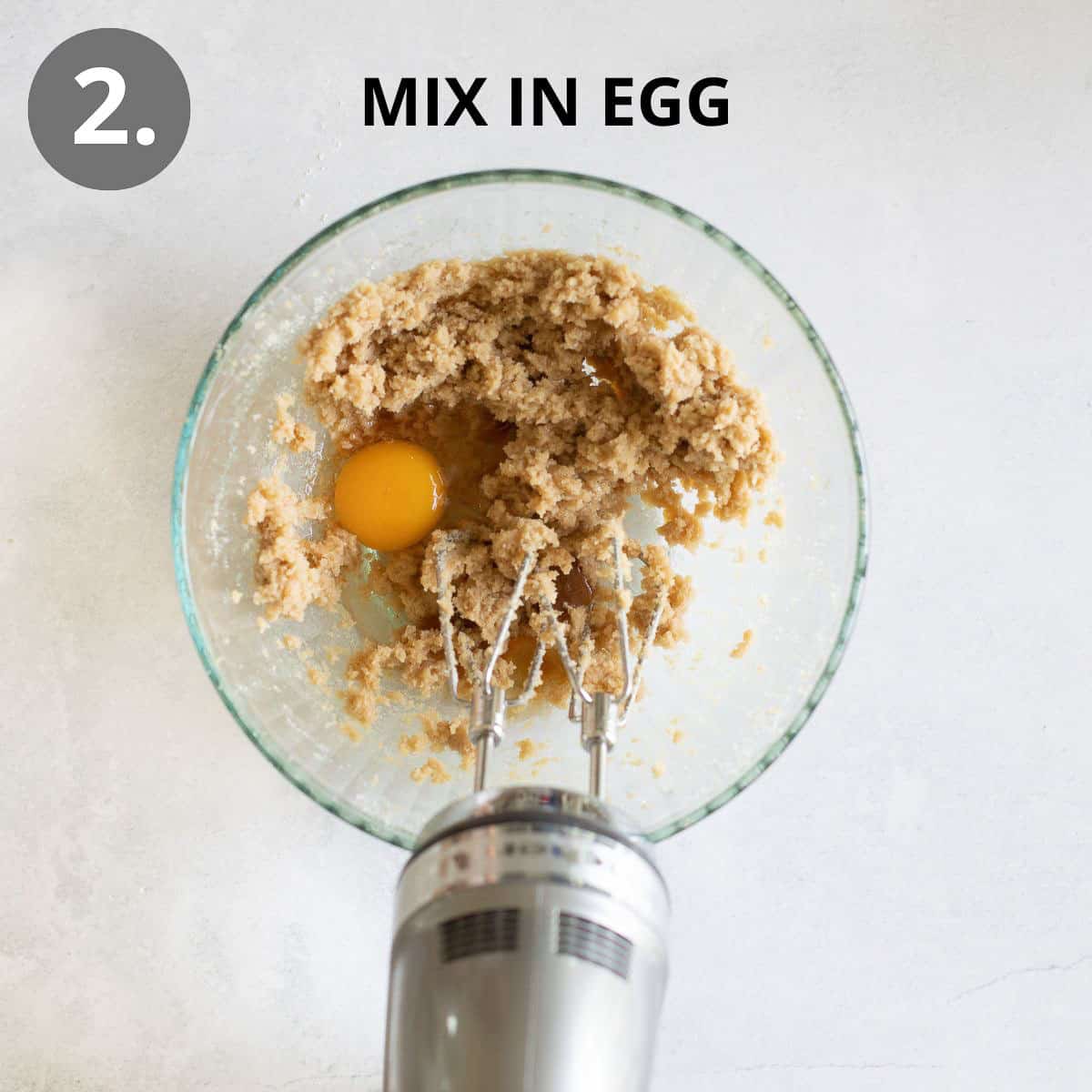 Egg, butter, and sugar being mixed in a glass mixing bowl