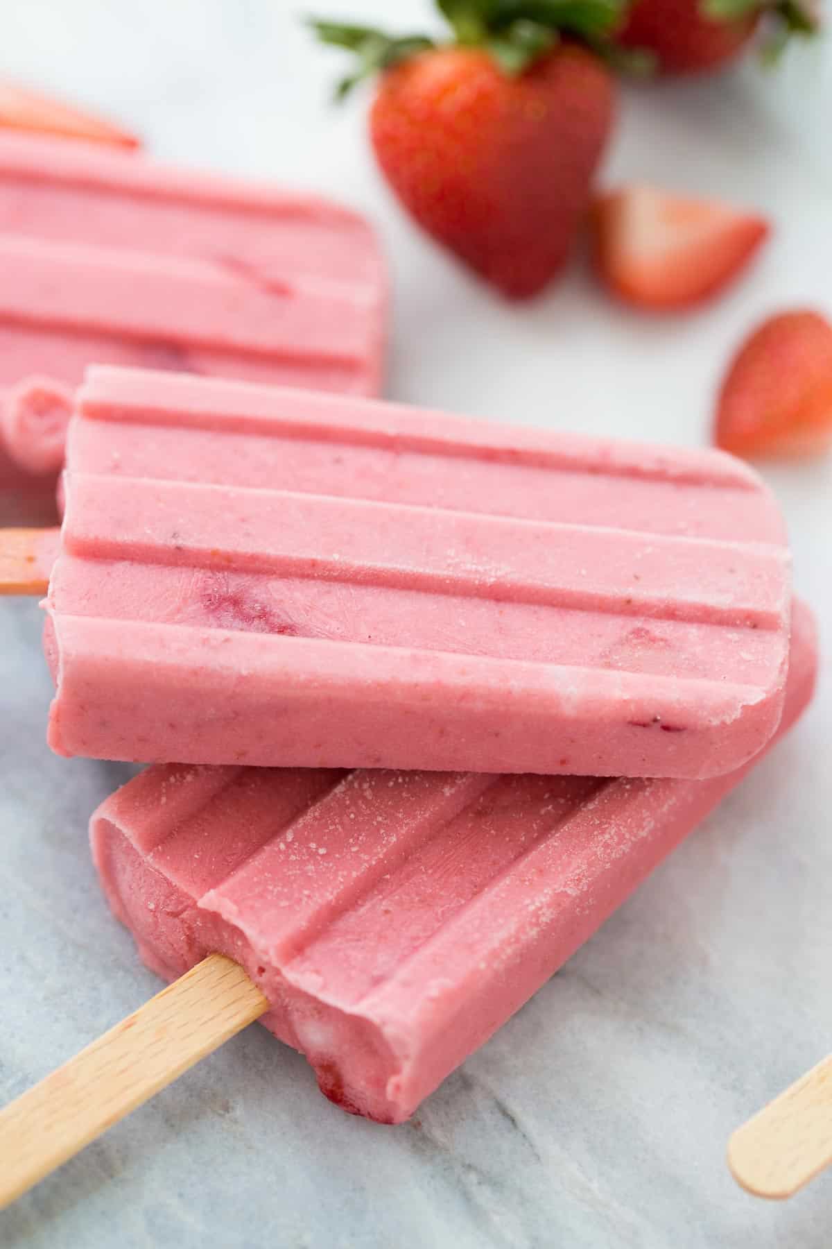 2 fruit popsicles stacked on top of each other on marble background