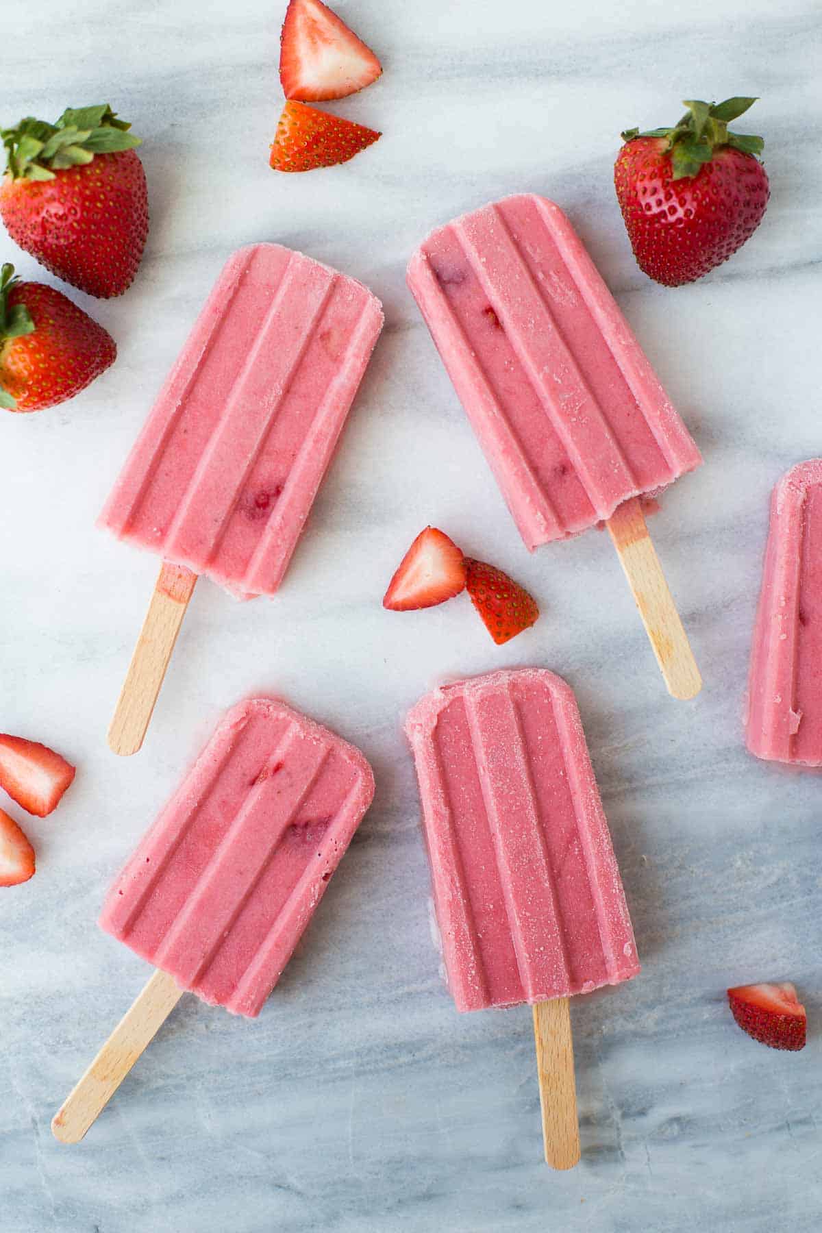 overhead shot of strawberry popsicles on marble background