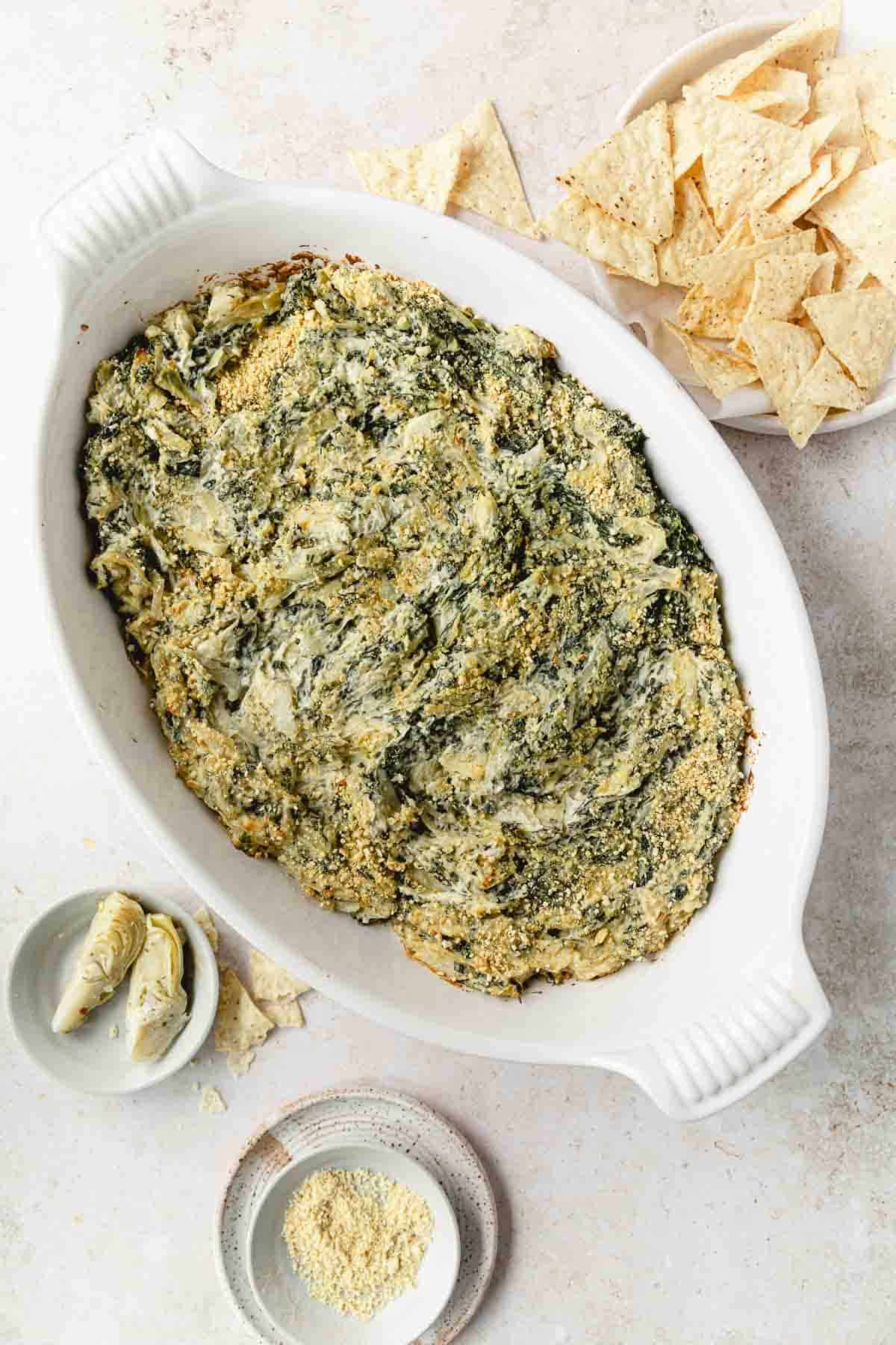 overhead shot of baked artichoke dip with chips on white background