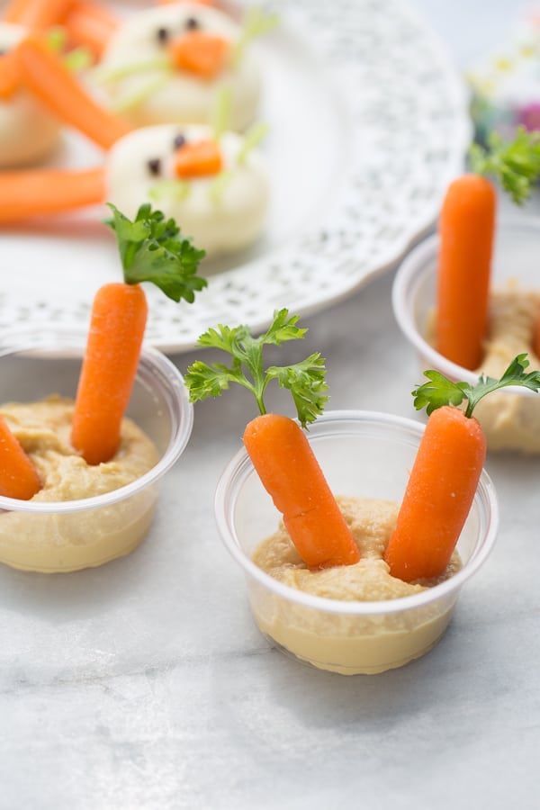 carrots topped with parsley in hummus cups
