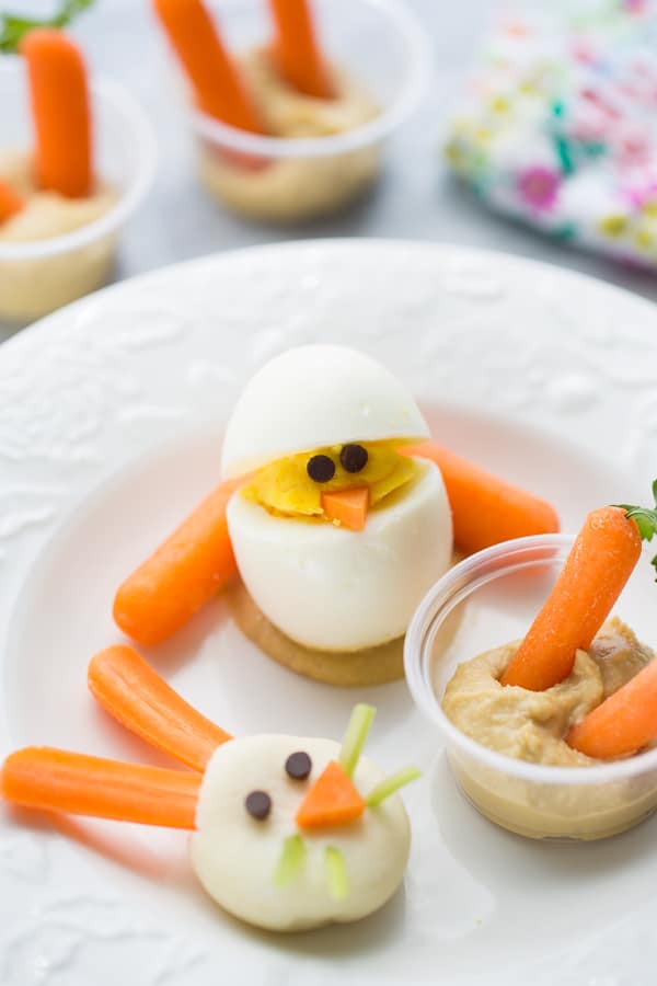 hard boiled egg chick, hummus/carrot snack and bunny face on white plate
