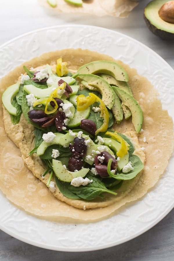 healthy gluten free hummus wrap with cucumber, avocado, olives, spinach, and feta