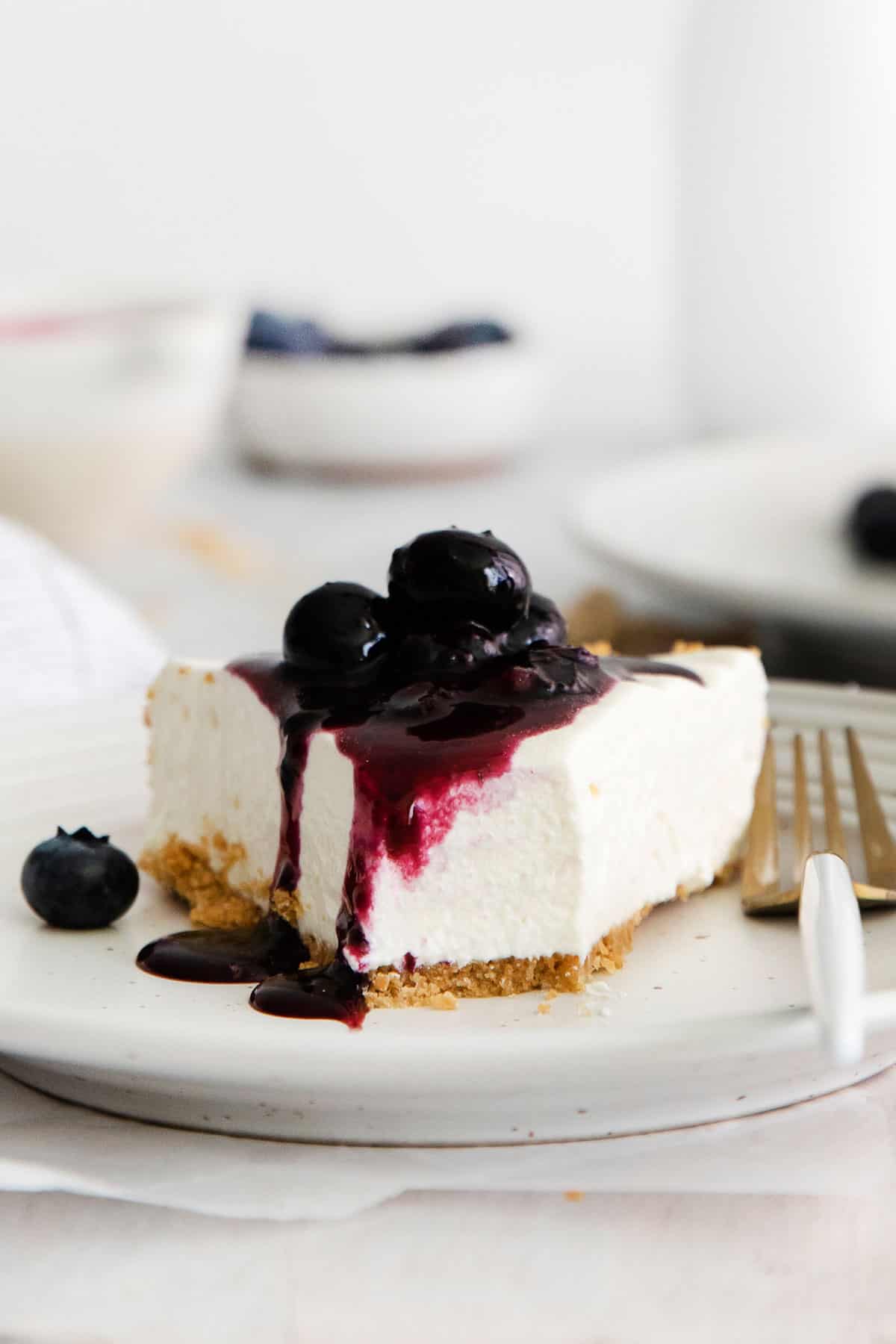 A slice of gluten-free no-bake cheesecake on a plate with blueberries on top
