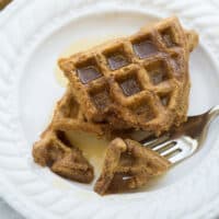 buckwheat waffles on white plate with syrup and fork