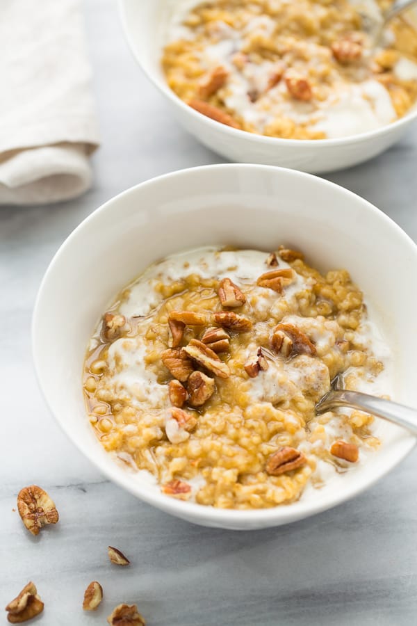 white bowl with oatmeal topped with milk and pecans