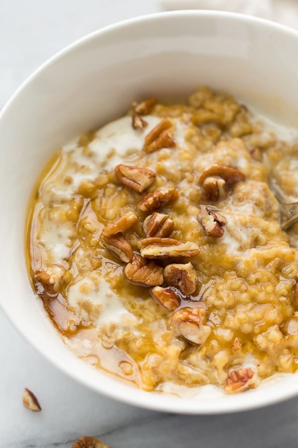 close up shot of oatmeal topped with pecans in white bowl