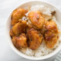 sticky chicken over rice in white bowl