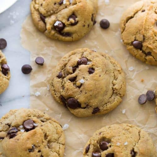 chocolate chip cookies topped with sea salt on brown parchment paper