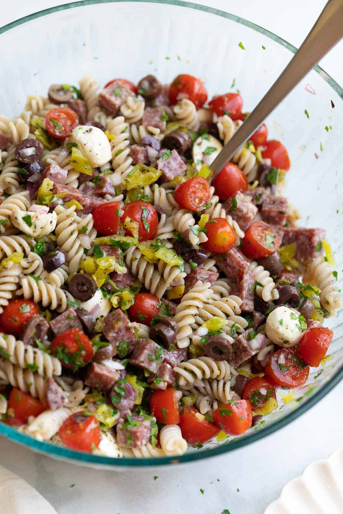 Pasta salad mixed in a large glass bowl