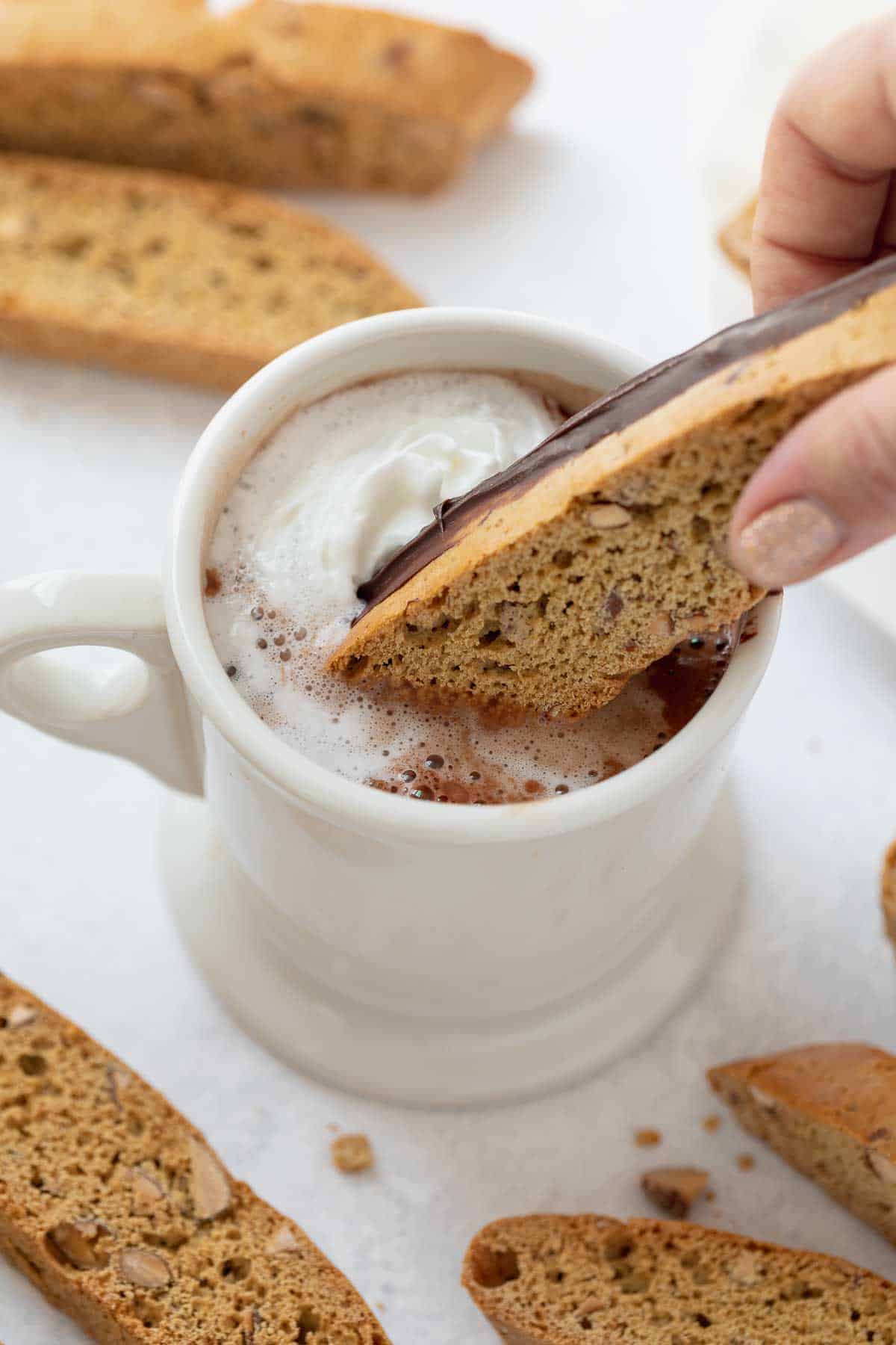 gluten free biscotti being dipped into a mug of hot cocoa