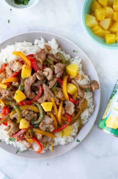 pork pineapple stir fry over rice on gray plate with can of Dole pineapple