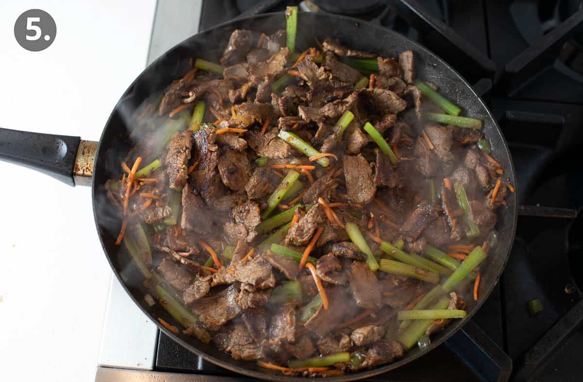 Beef, carrots, and peppers cooking in a skillet