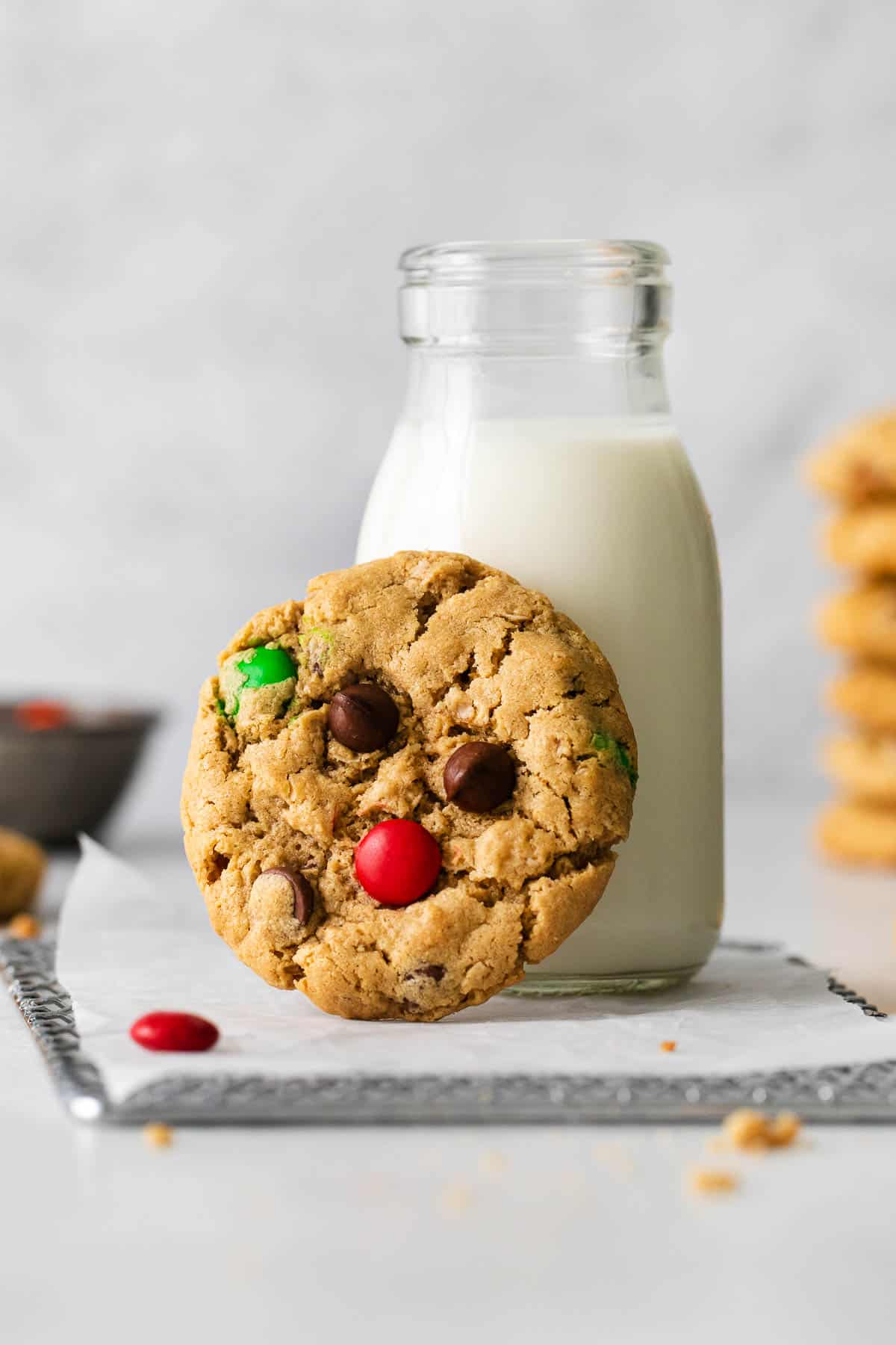 A gluten-free monster cookie leaning up against a jar of milk