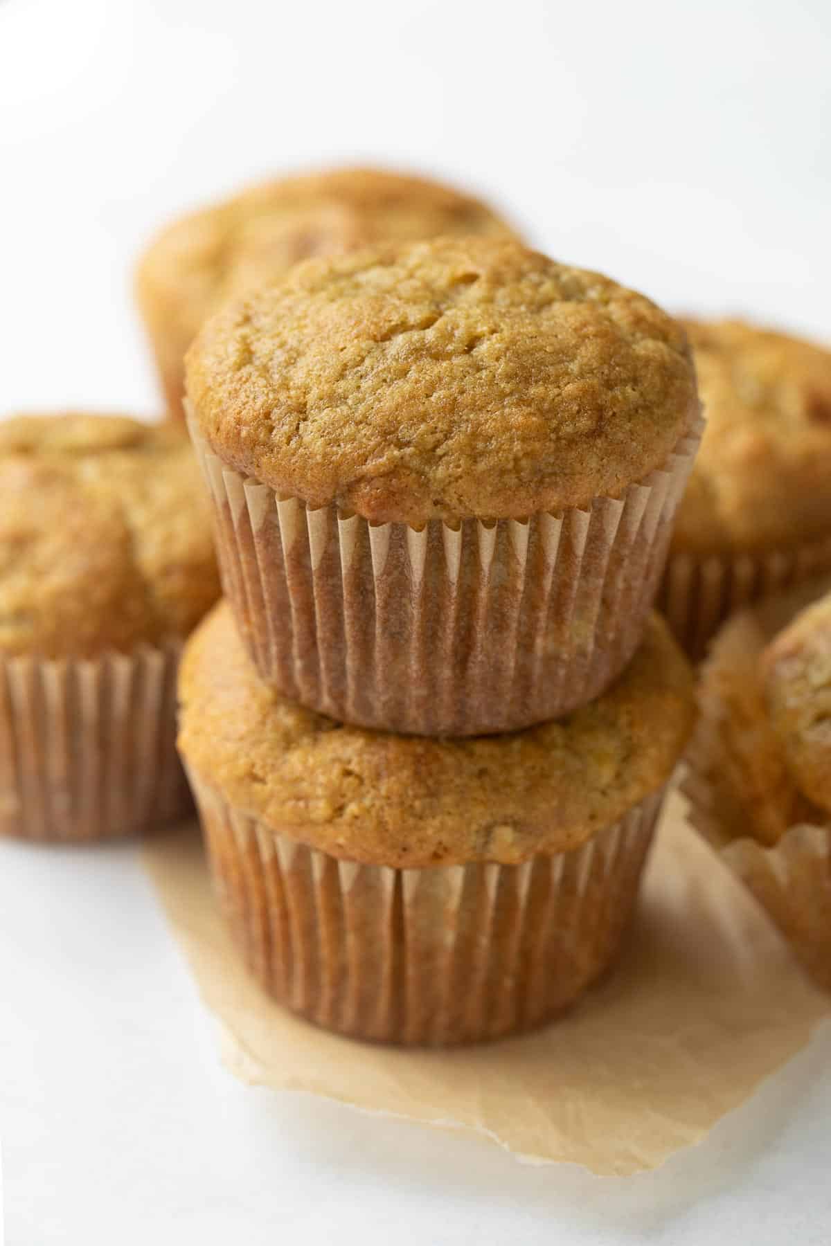 gluten-free banana muffins stacked on brown parchment
