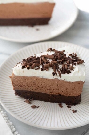 slice of chocolate mousse cake on white plate topped with chocolate shavings