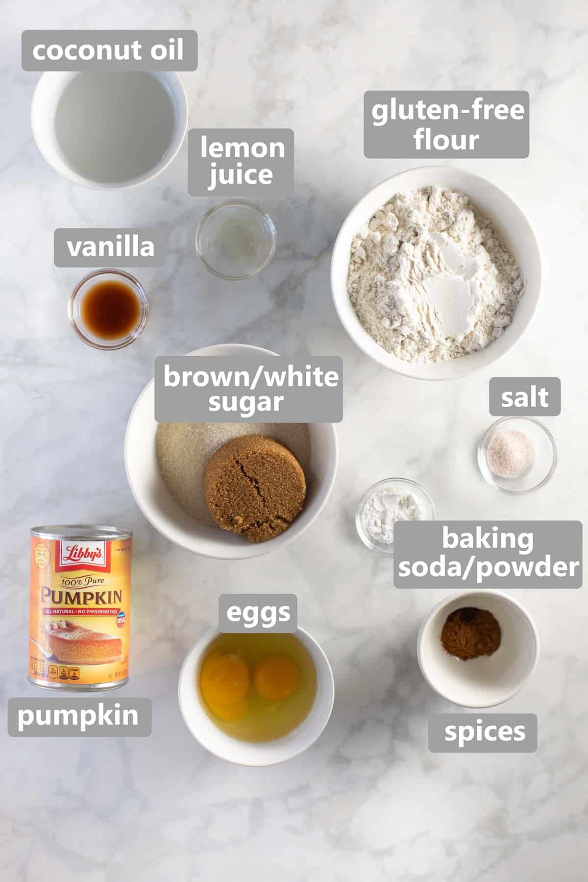 ingredients to make pumpkin muffins set out in bowls on marble background