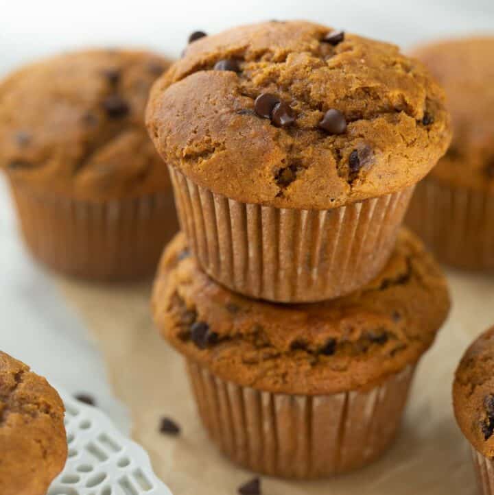 2 pumpkin muffins stacked on brown parchment paper with chocolate chips
